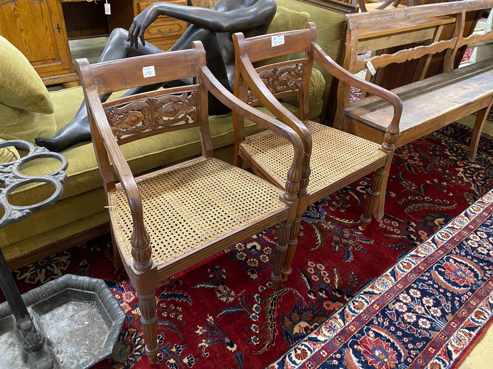 A pair of Indonesian caned hardwood elbow chairs, width 55cm, depth 44cm, height 86cm
